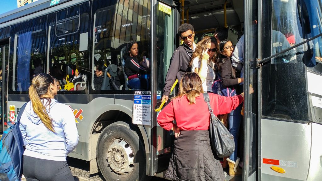 Transporte coletivo lotado com pessoas na porta