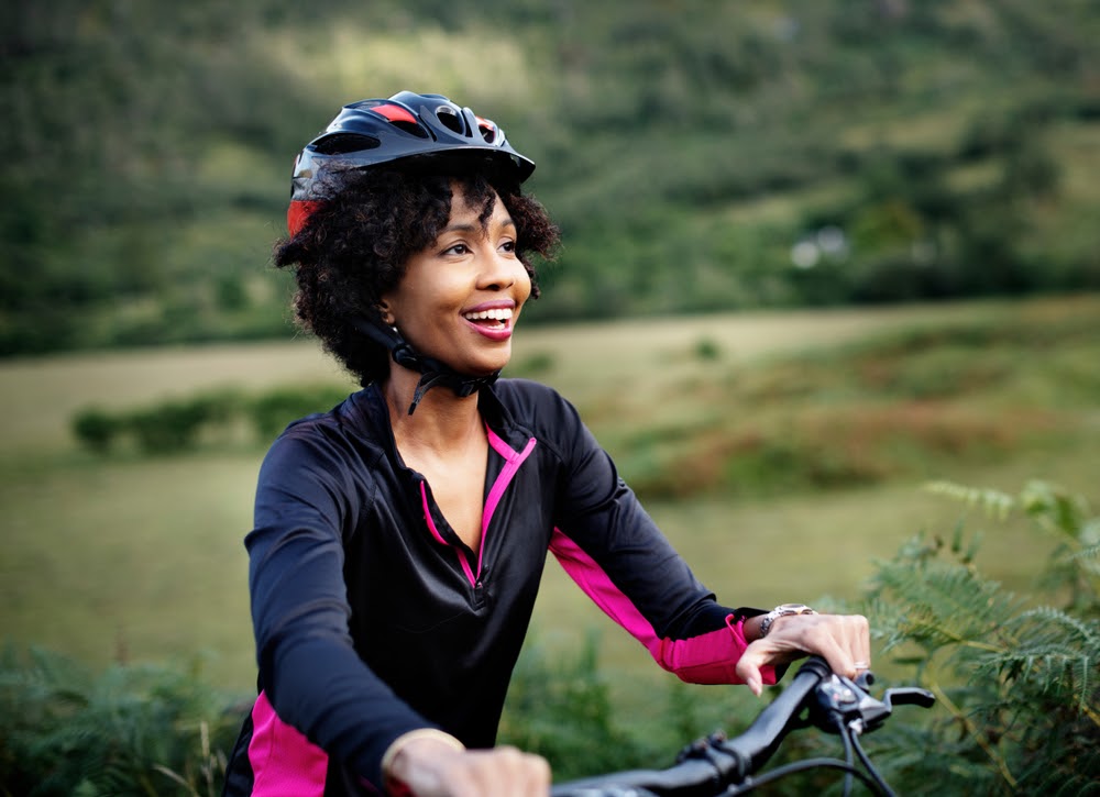 Mulher sorrindo andando de bicicleta com capacete