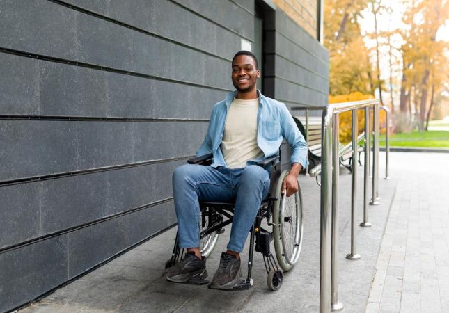 imagem de um homem negro sorrindo sentando em uma cadeira de rodas 