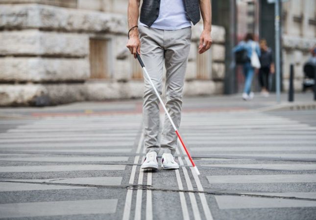 imagem de uma pessoa andando com uma guia dobrável para o uso de pessoas com deficiência visual