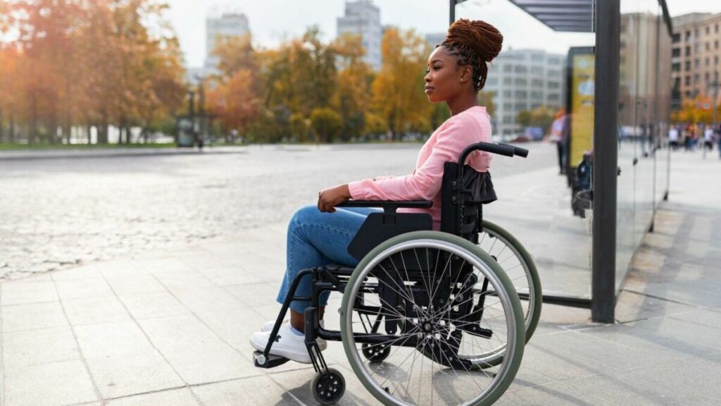imagem de uma mulher jovem negra sentada em uma cadeira de rodas